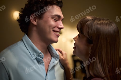 Preview: Young Man Smiling at Young Woman Indoors during Evening