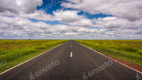 Preview: Scenic view of a long, winding road stretching out into the horizon with lush, green meadows.
