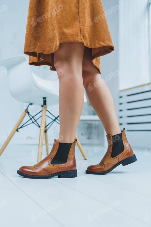 Preview: Close up of female legs in brown leather Chelsea boots. New autumn collection of women's shoes