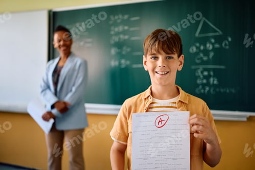 Preview: Happy elementary student getting A+ grade on a test at school and looking at camera.