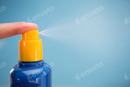 Preview: Finger Spraying Sun Tan Lotion With Copy Space On Blue Background