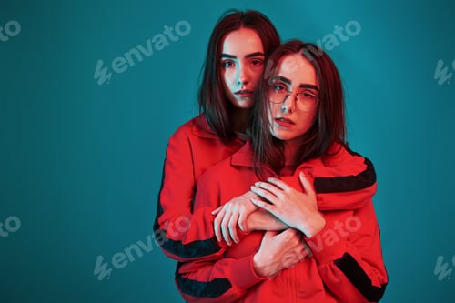 Preview: I will protect you. Studio shot indoors with neon light. Photo of two beautiful twins