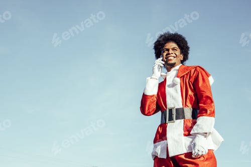 Preview: Smiling young african american santa claus talking on the phone