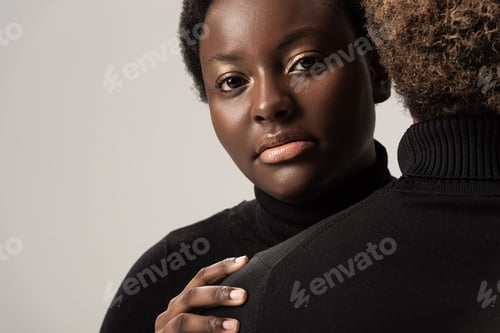 Preview: african american women in black turtlenecks hugging isolated on grey