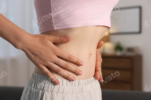 Preview: Woman with flat belly at home, closeup