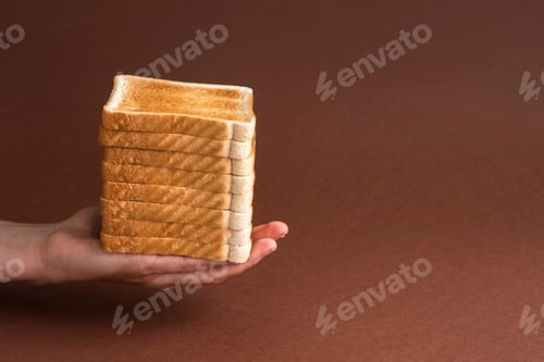 Preview: Heap of toasts in hand on brown