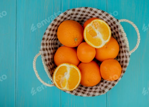 Preview: top view of fresh ripe oranges in a wicker basket on blue background