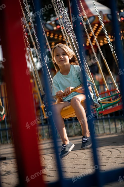 Preview: girl 7 years old rides in the park in the summer on an amusement ride
