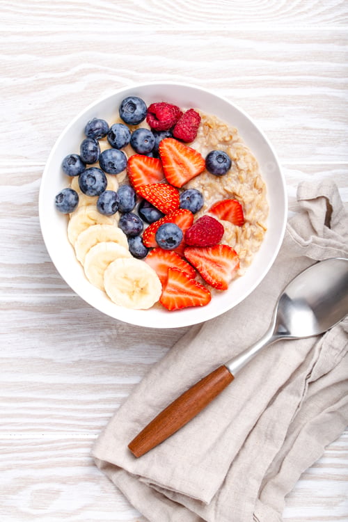 Preview: Oatmeal porridge with fruit and berries on white wooden table