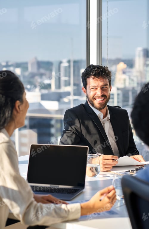 Preview: Happy professional young latin business man working with team in boardroom.