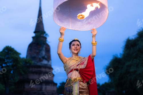 Preview: Asian women wearing thai dress releasing sky lantern into the night sky in yi peng festival