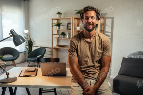 Smiling Man with Curly Hair Sits on Desk