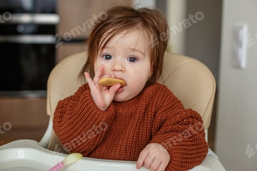 Preview: Baby girl sits on chair for feeding. Toddler eats baby biscuits and fruit puree.