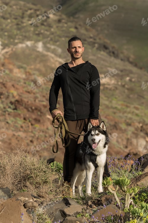 Preview: Sportive confident man with dog on rocks