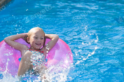 Preview: Girl lying on her back on inflatable ring in garden swimming pool