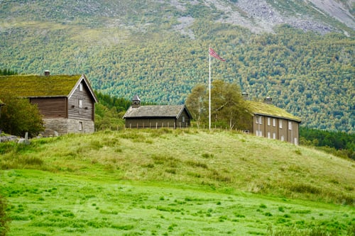 Preview: Traditional wooden houses on a grassy hill with a Norwegian flag