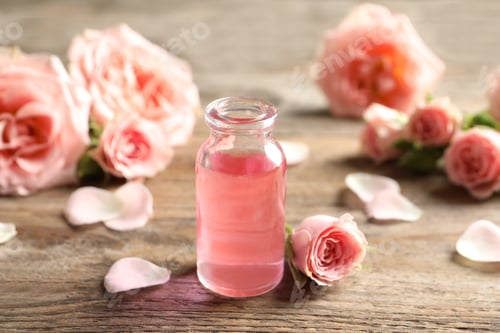 Preview: Bottle of rose essential oil and flowers on wooden table