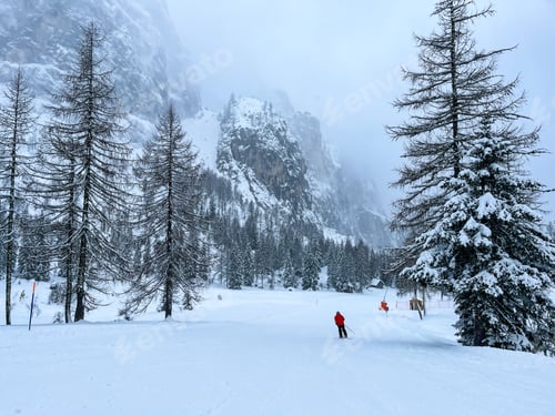 Preview: Picturesque winter scene with a ski slope surrounded by trees and mountains in the background