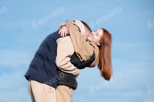 Preview: cheerful romantic couple dating and hugging outdoors, sky background