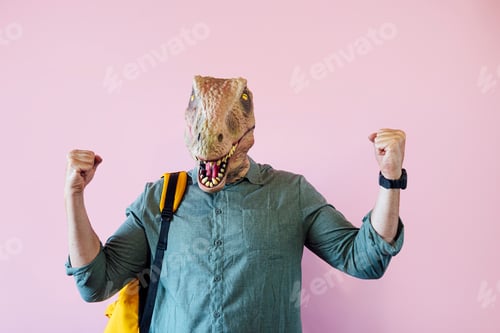 Preview: Man with lizard mask on pink background showing his muscles.