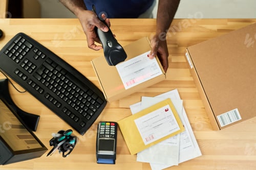 Preview: Young Adult Black Man Scanning Parcel Label While Working at Shipping Desk