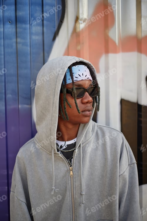Preview: Young Black Man Wearing Hoodie and Sunglasses Standing Against Graffiti Wall