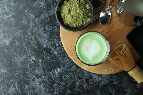 Preview: Glass of matcha latte and accessories for making on black smokey table