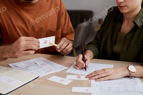 Preview: Male tutor of Chinese language pointing at paper card with hieroglyph