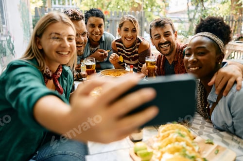 Preview: Happy friends having fun while taking selfie with cell phone in a cafe.