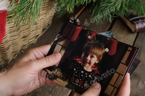 Preview: Hands flipping through Christmas printed photos for family picture album.