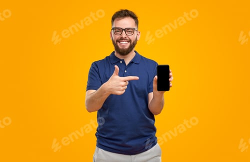 Preview: Smiling Man Points to Phone on Yellow Background