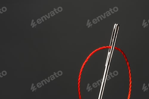 Preview: Needle with sewing thread on dark background, closeup
