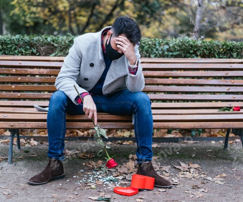 Preview: Shallow focus shot of a young male sitting on the bench after losing his love