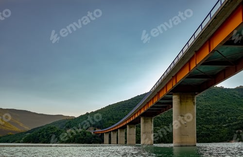 Preview: Low angle view of a Concrete bridge surrounded by the river and hills covered in forests