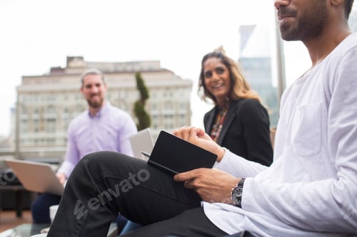 Preview: Businessman writing in notebook while sitting with colleagues at restaurant
