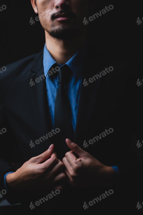 Preview: handsome confident businessman wearing and adjusting the black suit