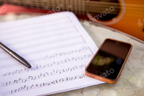 Preview: Sheet music and a smartphone ready for a creative jam session with a guitar in the background.
