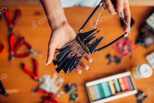 Preview: Female person holds handmade necklace, needlework