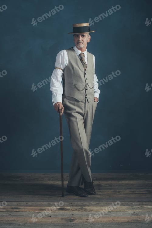 Preview: Retro 1920S Dandy In Suit Standing With Cane In Front Of Gray Wall.