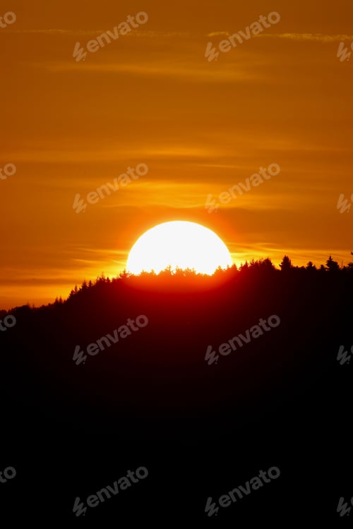 Preview: Sunset over forested horizon with vibrant orange sky