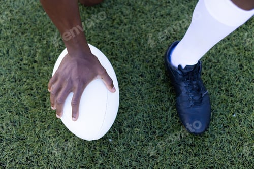 Preview: African American young male athlete model holding rugby ball on field outdoors on grass