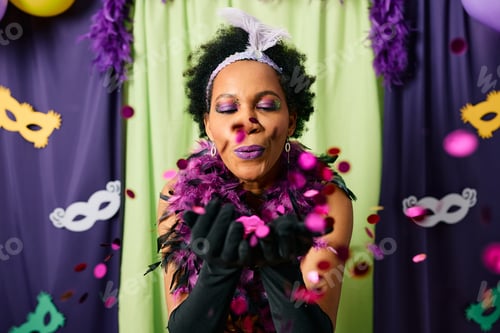 Preview: Black woman blowing confetti while celebrating Mardi Gras carnival.