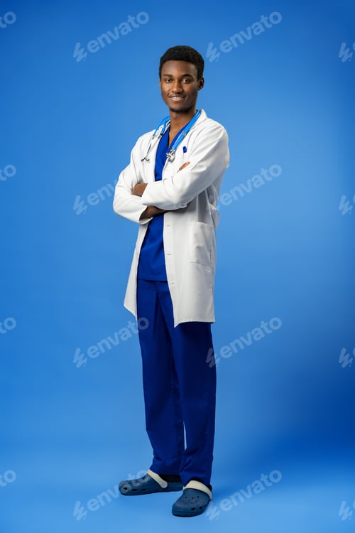 Preview: Confident black doctor posing over blue studio background