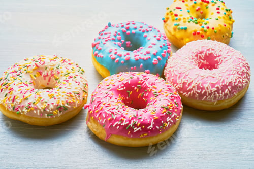 Preview: Assorted donuts with colorful frosted, pink glazed, and sprinkles on the blue table