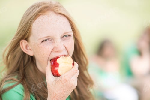 Preview: Portrait of girl with red hair eating an apple