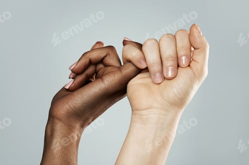 Preview: A pinky promise gesture between African and Caucasian women. Closeup of palms on gray background.