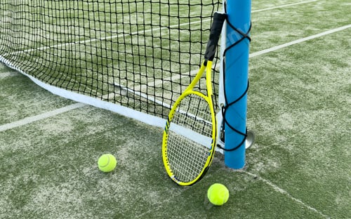 Preview: Tennis racket lying on net with tennis ball in hard surface court