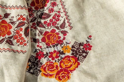 Preview: Ukrainian clothes embroidered shirt. Red orange and black threads background. Vyshyvanka is a symbol