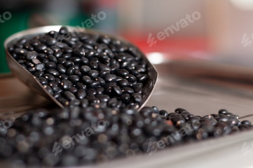Preview: Pile of black beans sprinkled on weighing scales. Scoop of black beans. Detailed photo.