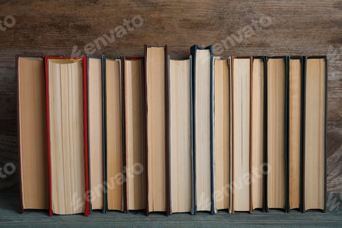 Preview: Stack of hardcover books on light blue table against wooden background
